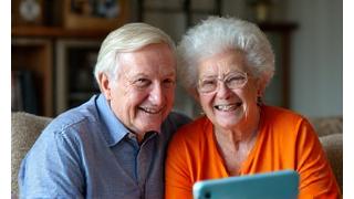 Coppia anziana sorridente che interagisce con un tablet, segno di vitalità e tecnologia